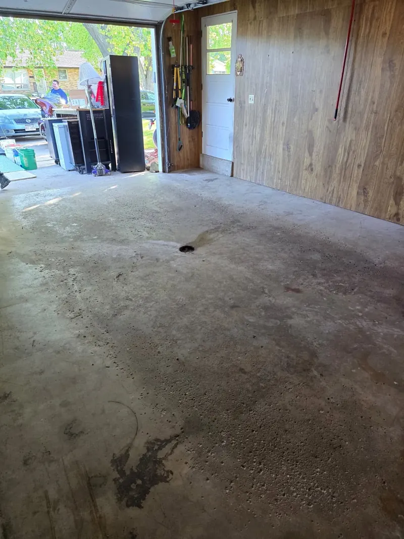 Pitted, oil-stained garage slab around a floor drain before coating in Allouez, WI