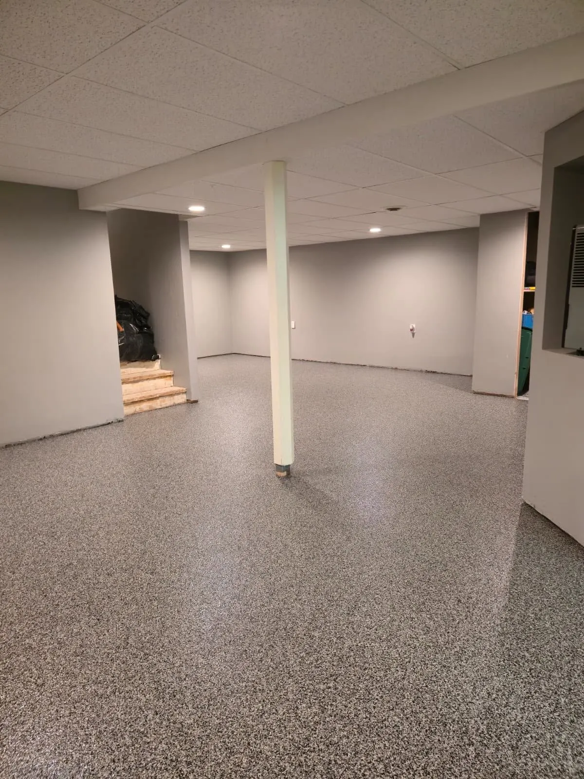 Finished basement with light flake epoxy floor and support column