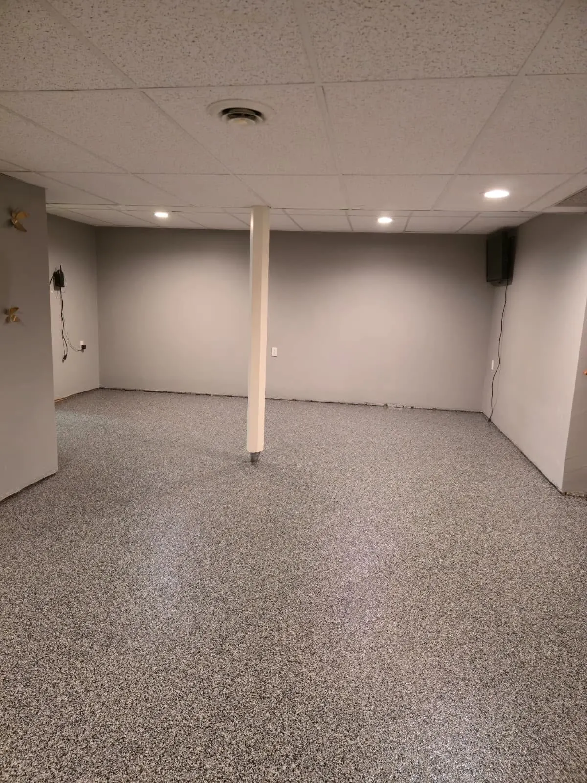 Basement room with flake epoxy floor around structural post