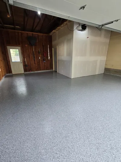 Finished Feather Gray flake floor in a 2-car garage with drywall and wood walls in Marinette, WI
